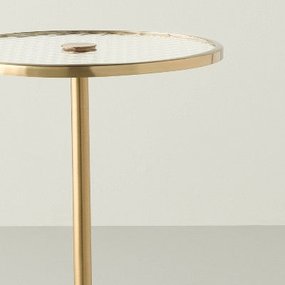 Okrągły stolik pomocniczy z blatem szklanym i metalową podstawą w kolorze mosiądzu